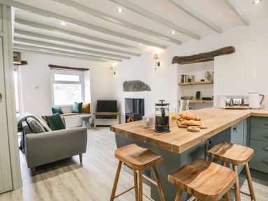 A living room with a kitchen island with stools croissants and coffee maker at Turn Cottage in Satterthwaite near Hawkshead