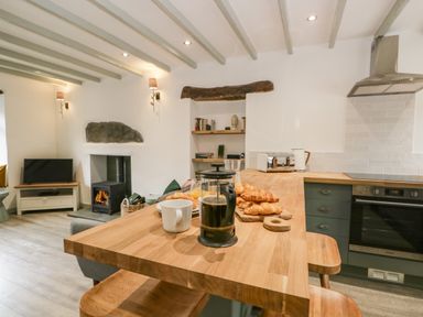 A kitchen with a wooden countertop holding a coffee press croissants and a mug at Turn Cottage in Satterthwaite near Hawkshead