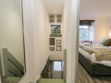 A stairway with framed pictures on the wall next to a bedroom with a bed and a window at Turn Cottage in Satterthwaite near Hawkshead