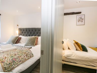 Two bedrooms separated by a door each with a bed and multiple pillows at Turn Cottage in Satterthwaite near Hawkshead