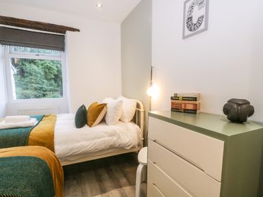 A bedroom with a single bed a chest of drawers books and a window at Turn Cottage in Satterthwaite near Hawkshead