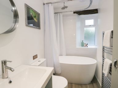 A bathroom with a freestanding bathtub shower curtain radiator and a sink at Turn Cottage in Satterthwaite near Hawkshead