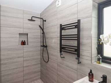 A bathroom with a shower, towel rail and soap dispenser at The Cadeleigh near Tiverton