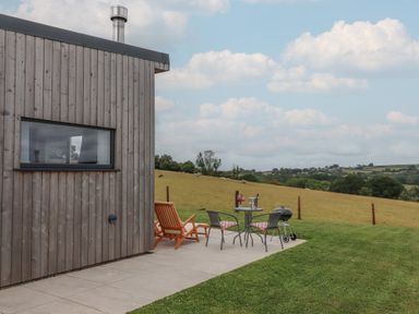 An outdoor space with a wooden building and seating area at The Cadeleigh in Cadeleigh near Tiverton