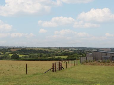 A view of a field with trees and a building at The Cadeleigh near Tiverton