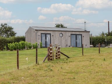 A house with a wooden exterior and a fence at The Pennymoor in Cadeleigh near Tiverton