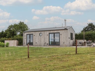 A house with wooden exterior and patio furniture at The Pennymoor Cadeleigh near Tiverton