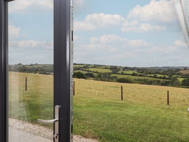 A view of hills and grass from an open door at The Pennymoor in Cadeleigh near Tiverton