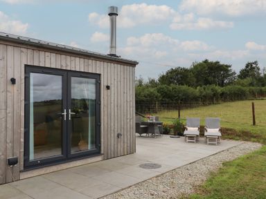 An outdoor area with a wooden building and patio furniture at The Pennymoor in Cadeleigh near Tiverton