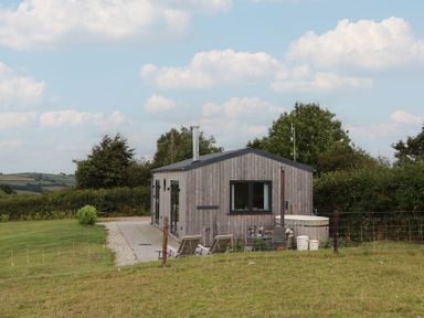 A wooden house with a pathway and grass area at The Pennymoor Cadeleigh near Tiverton