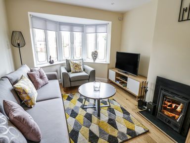A living room with a sofa armchair round coffee table television and fireplace at Globe Cottage in Stratford-Upon-Avon