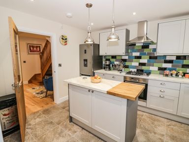 A kitchen with an island and colorful tiled backsplash at Globe Cottage in Stratford-Upon-Avon