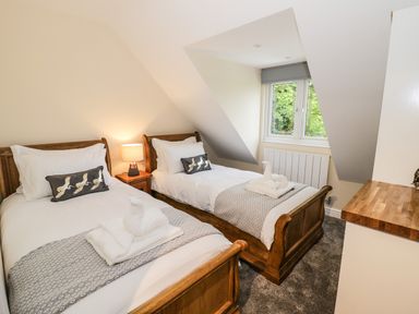 A bedroom with two single wooden beds a window and a bedside table with a lamp at Globe Cottage in Stratford-Upon-Avon