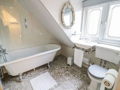 A bathroom with a clawfoot bathtub a sink a toilet and a patterned tile floor at Globe Cottage Stratford-Upon-Avon