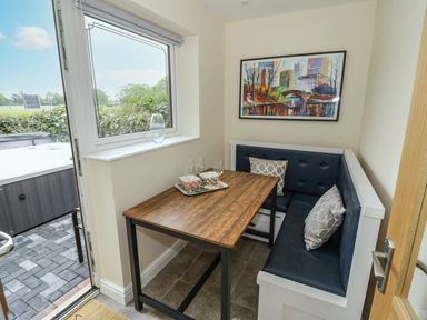A small dining nook with a wooden table and blue cushioned bench seating with pillows at Globe Cottage in Stratford-Upon-Avon