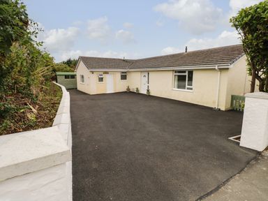 A single-story house with a paved driveway and small plants near the doors at Trem Y Morfa in Newport Pembrokeshire