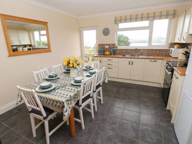 A kitchen with a dining table set for six and yellow flowers on the table at Trem Y Morfa Newport Pembrokeshire