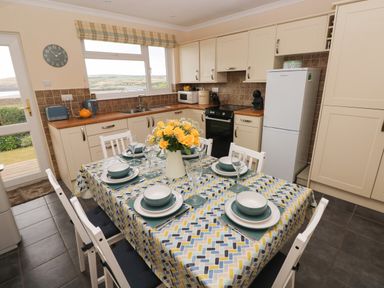 A kitchen with a dining table set for six with yellow flowers on the table at Trem Y Morfa in Newport Pembrokeshire