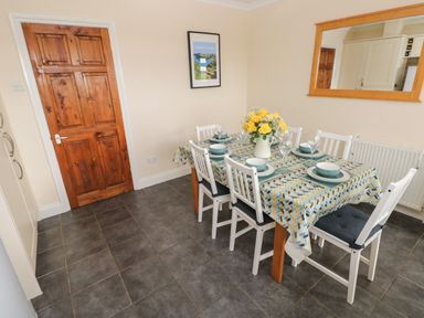 A dining room with a table set for six with dishes and flowers at Trem Y Morfa in Newport Pembrokeshire