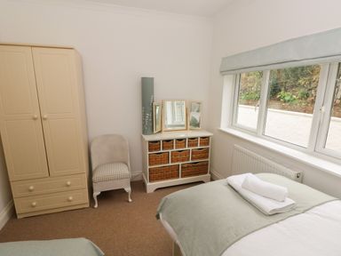 A bedroom with a bed, a wardrobe, a chair, a dresser with mirrors, and a window at Trem Y Morfa in Newport Pembrokeshire