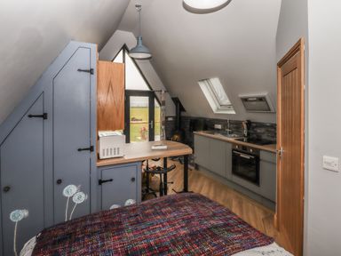 A small kitchen and bedroom area with cabinets stovetop and bed at Silver Birch Lodge in Misterton