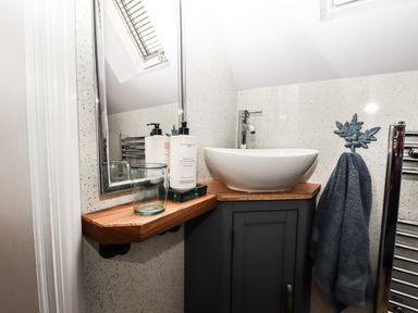 A bathroom sink with a wooden countertop a mirror soap dispenser a glass and a towel hanging on a hook at Silver Birch Lodge in Misterton