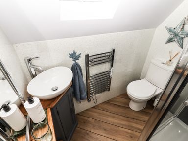 A bathroom with a white sink on a wooden cabinet a toilet a towel rack and a shower enclosure at Silver Birch Lodge in Misterton