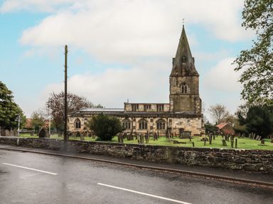 An exterior view of a church with a graveyard and stone wall beside a road at Silver Birch Lodge in Misterton