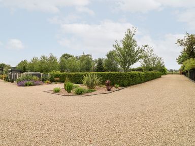 A gravel driveway with bushes and plants along the sides at Silver Birch Lodge in Misterton