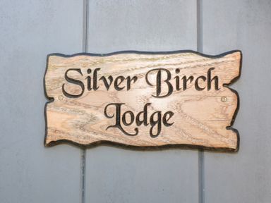 A wooden sign with the words Silver Birch Lodge on a gray wall at Silver Birch Lodge in Misterton