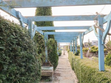 A garden pathway with blue wooden pergola and green hedges at Silver Birch Lodge in Misterton