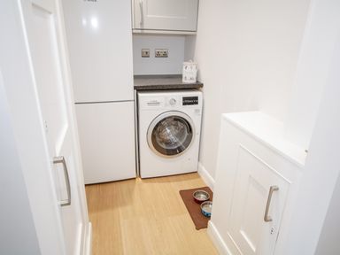 A laundry room with a washing machine refrigerator and storage cabinets at 14 Parc Delfryn Brynteg near Benllech