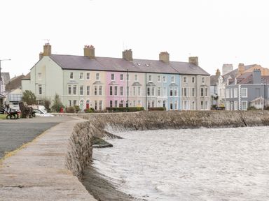 A row of pastel colored houses along a waterfront promenade at 14 Parc Delfryn in Brynteg near Benllech