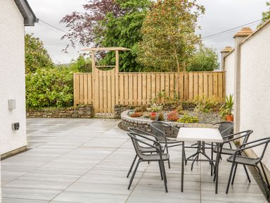 An outdoor patio with a table and four chairs near a garden bed and wooden fence at Wee Andy's Slavary near Buncrana County Donegal