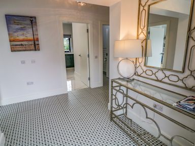 A hallway with patterned tile floor a table with round lamp and large decorative mirror at Wee Andy's Slavary near Buncrana County Donegal