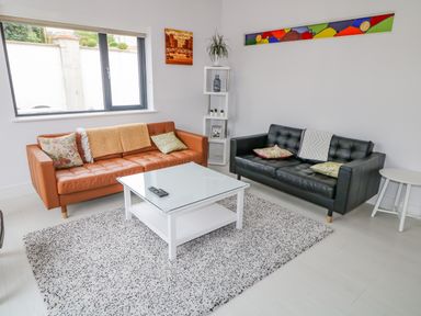 A living room with two sofas a glass coffee table a white shelf and wall art at Wee Andy's Slavary near Buncrana County Donegal