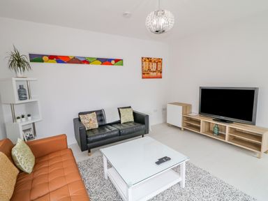 A living room with two sofas a white coffee table a TV on a wooden stand and artwork on the walls at Wee Andy's in Slavary near Buncrana County Donegal