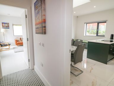A hallway with a painting on the wall and doors to a living room and kitchen at Wee Andy's in Slavary near Buncrana County Donegal
