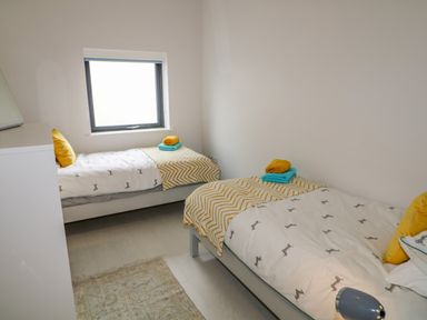 A bedroom with two single beds each with folded towels and a window at Wee Andy's Slavary near Buncrana County Donegal