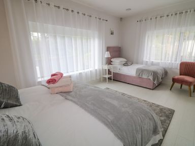 A bedroom with two beds a nightstand with a lamp and a chair at Wee Andys Slavary near Buncrana County Donegal
