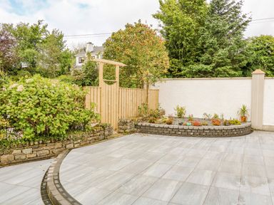 An outdoor paved patio area with raised stone flower beds and a wooden gate at Wee Andy's in Slavary near Buncrana County Donegal