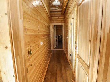 A wooden hallway with doors on the right and a room visible at the end at Elm Lodge in Greetham Rutland