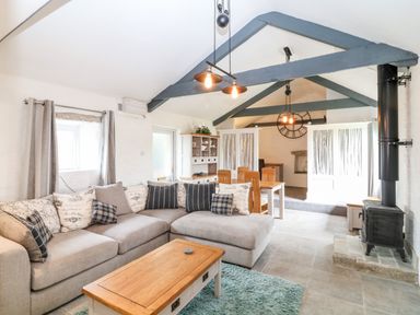 A living room with a sectional sofa and coffee table next to a wood stove at Polgear View Polgear Nr Redruth