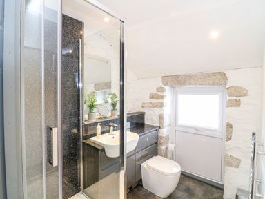 A bathroom with a shower cabin a sink a toilet and a window at Polgear View in Polgear Nr Redruth