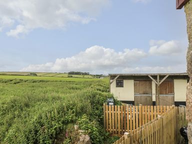 A fenced area with a small building and green fields in the background at Polgear View Polgear Nr Redruth