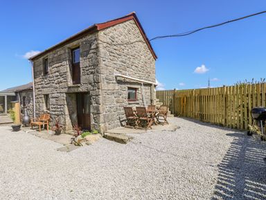 A stone house with outdoor wooden chairs and table on gravel at Polgear View in Polgear Nr Redruth