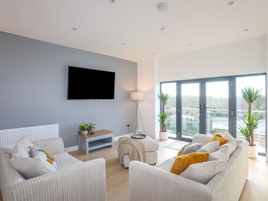 A living room with sofas cushions television and plants at Bryn Min Manton Apartment in Caernarfon