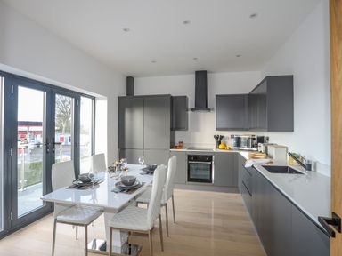 A modern kitchen with a dining table and chairs near large windows at Bryn Min Manton Apartment in Caernarfon