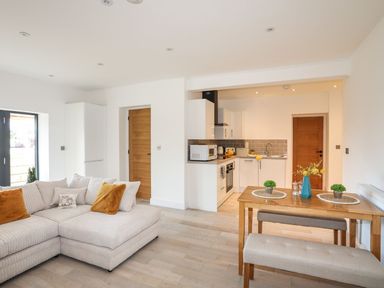 An open plan lounge and kitchen with a sofa and dining table at Bryn Min Manton Bach in Caernarfon