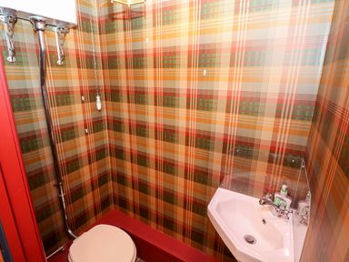 A bathroom with a wall-mounted toilet and a corner sink with soap dispensers at Bwthyn Canol in Haverfordwest